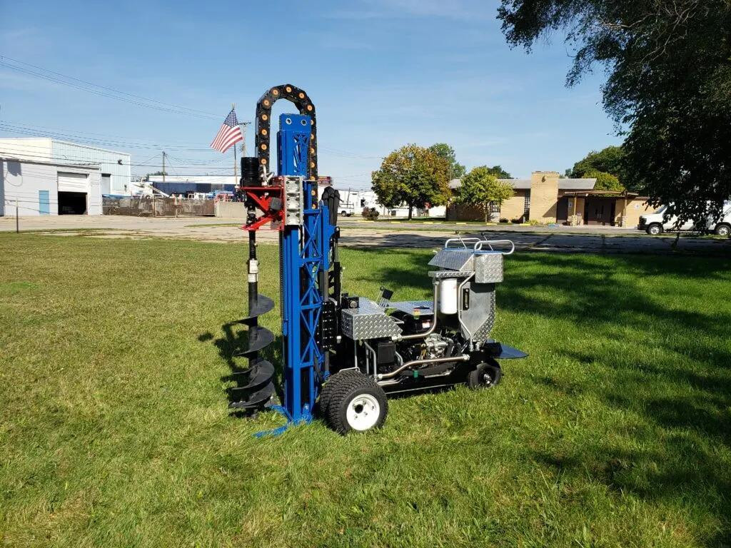 Machine de forage sur pelouse avec drapeau américain en arrière-plan.
